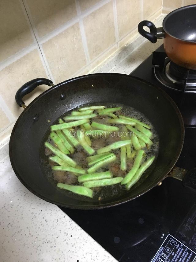 继续翻炒，(豆角皮起皱后)倒入水末过菜