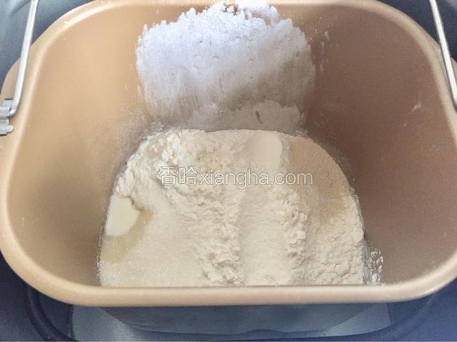 然后除开黄油之外的其他原料一次性倒入。面包机桶盐和酵母对角放好。
