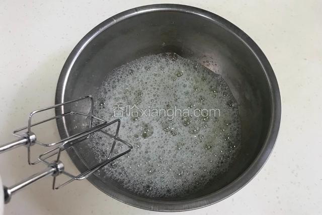 往蛋白内加入几滴柠檬汁，用手动打蛋器打低速打至粗泡，加入1/3细砂糖。