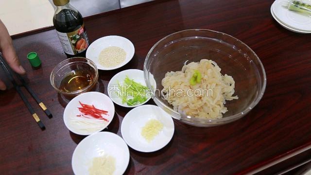 准备劲霸青芥辣，蒜蓉，詹王鸡粉，红椒丝，香菜梗段，葱白丝，香油；空盘内倒入魔芋结和海蜇，把以上准备好的辅料与调味料，依次加入盆内。