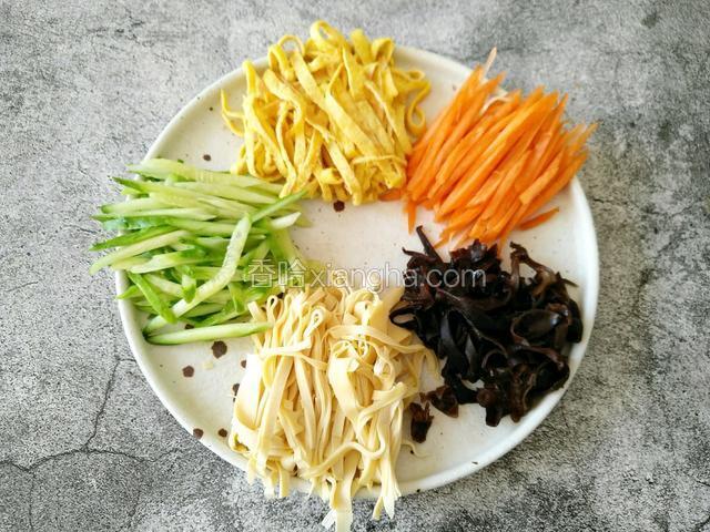 把刚才准备好的：黄瓜丝、鸡蛋饼丝、胡萝卜、豆皮、木耳码入盘中备用（一定要找一个大一点的盘子）。