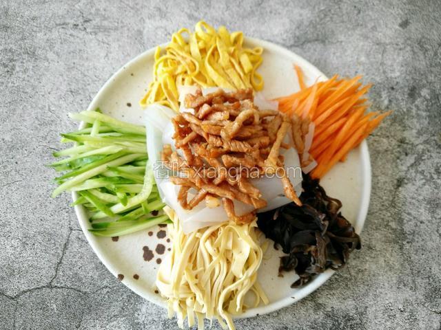 把焯好的肉丝码在拉皮上面。