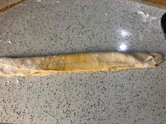 把薄面片切成两块叠在一起，再对折用刀切成面条状。