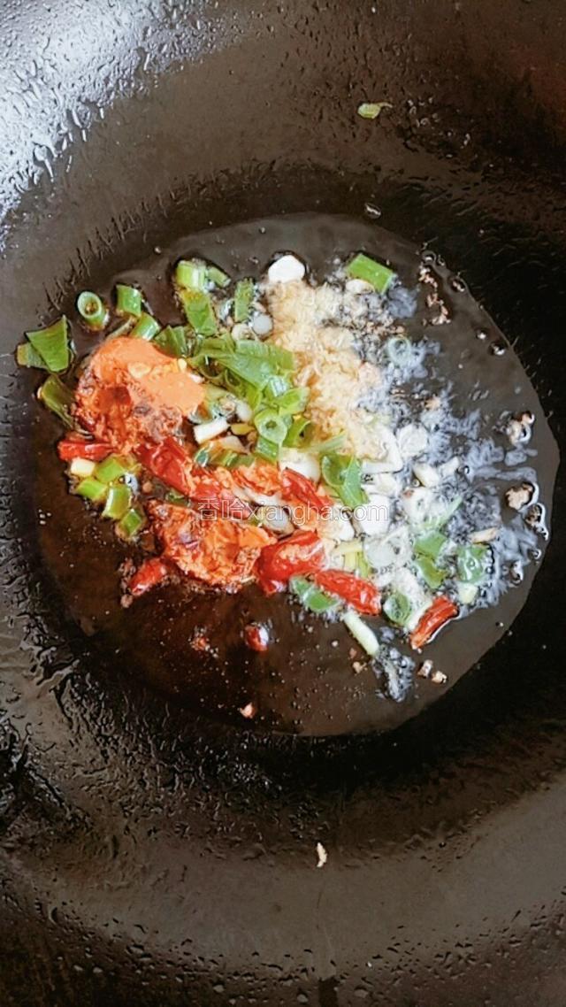 炉灶开火，锅内放适量油，油热放入剩下的蒜片，放入葱花、姜沫、红干椒、麻辣火锅底料炒香。