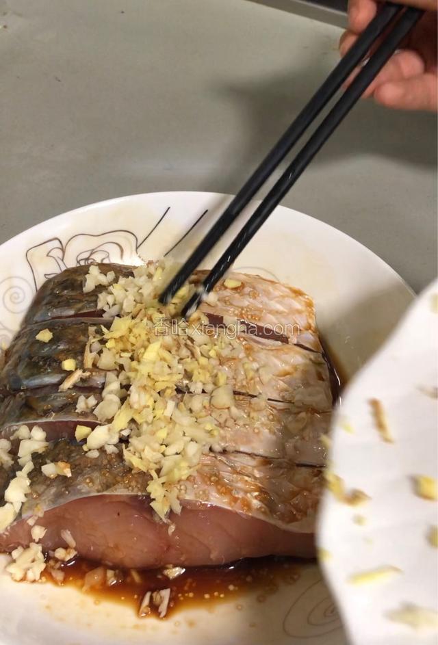 鱼身上均匀地撒上白糖，均匀放上切好蒜蓉，姜蓉。