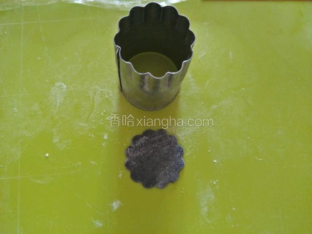 取黑色面团三克搓揉擀平，擀的不要太薄厚一些，用波浪模具按压。