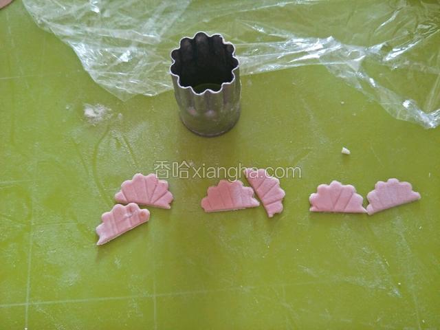 取3克粉色搓揉压三个波浪纹圆形，中间切开。
