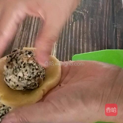 取一个面团，用手捏成厚饺子皮状，包入馅料后团圆。