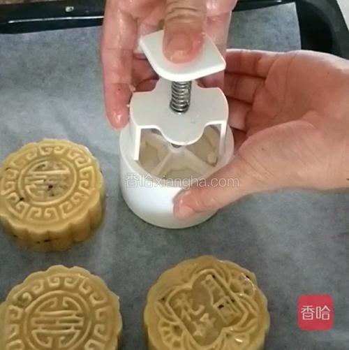 然后把模具倒扣在烤盘里，用手按压模具的弹簧杆，确保饼坯在模具里被压实。压实饼坯后轻轻提起模具，饼坯就会脱落出来，一个生月饼就成型了。