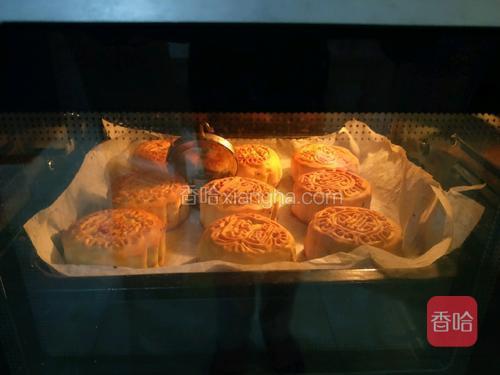 用喷壶往月饼坯上喷点水，烤箱180度预热10分钟后，放入烤盘。烤20分钟时，取出烤盘，用刷子将每块月饼刷上蛋黄液，放入烤箱后再烤5分钟取出。