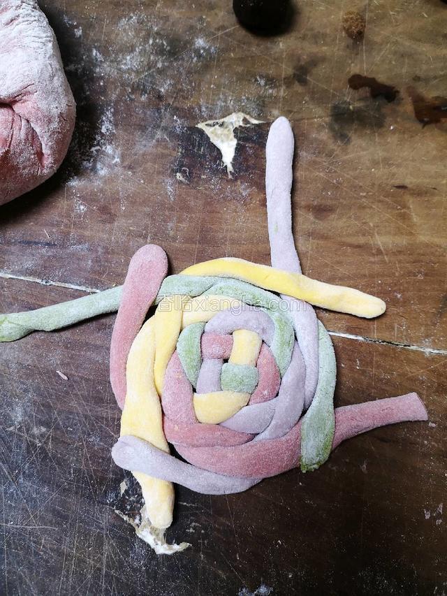 再逆时针将白，红，绿，黄四根面条压在与它平行的面条上，再顺时针逆时针重复上面的步骤，直到面条全部绕完。