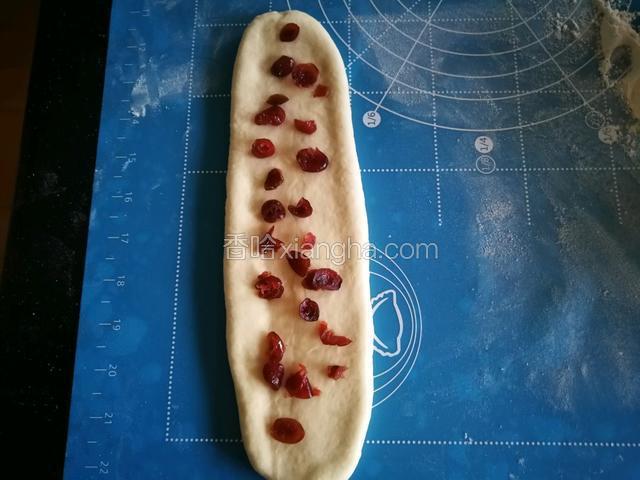 取一个擀成牛舌形状，放上蔓越莓干。