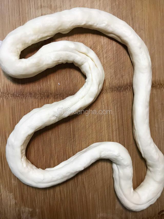 顺着小孔将面饼拉成一根粗绳状。