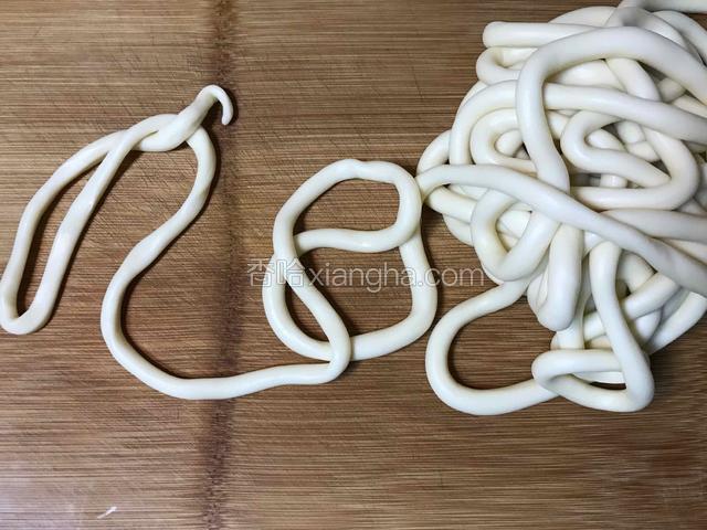 从任意处断开，在案板上将其搓成比成人小手略细的一根长条。（若是感到搓开后面条老是回弹或阻力很大，则可以继续盖上保鲜膜让其静置5分钟左右再接着搓）