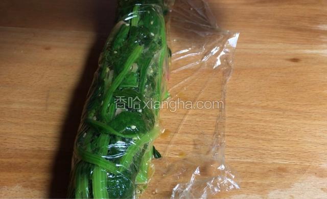 砧板上铺一层保鲜膜，放入菠菜边包边挤压成结实的条状