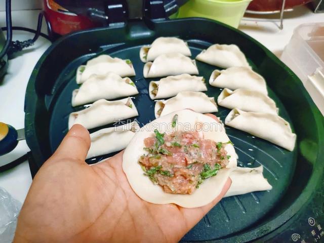 取一张饺子皮，将肉馅放在中间，饺子皮中间向两边捏紧，保留尾部不捏