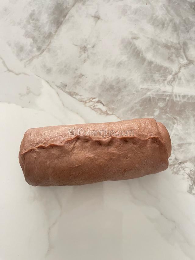 将撒满巧克力豆的面团卷好，尾部要收紧，如下图